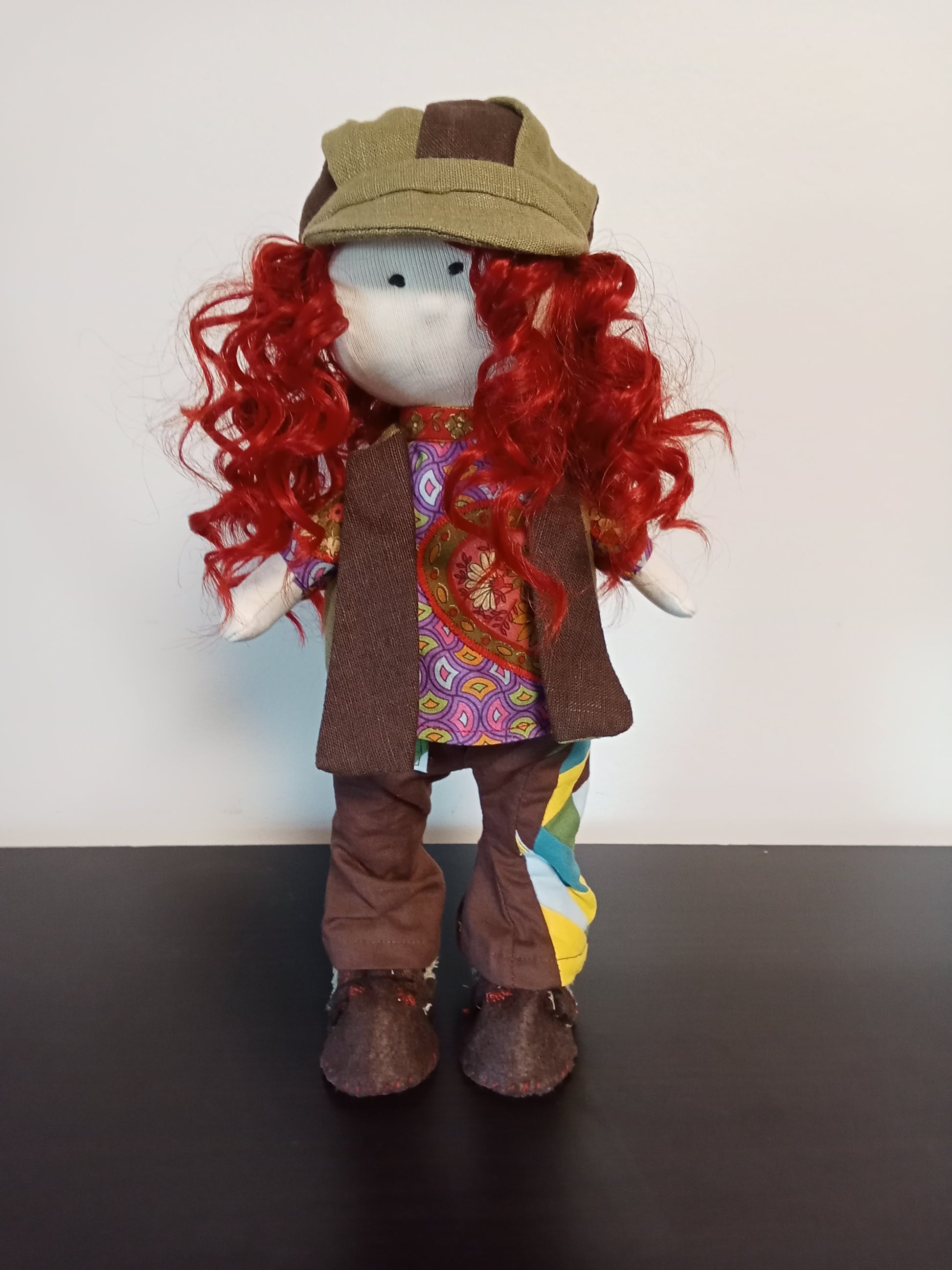 “Portrait of Handmade collectible doll with red curly hair wearing a colorful  unique outfit.”