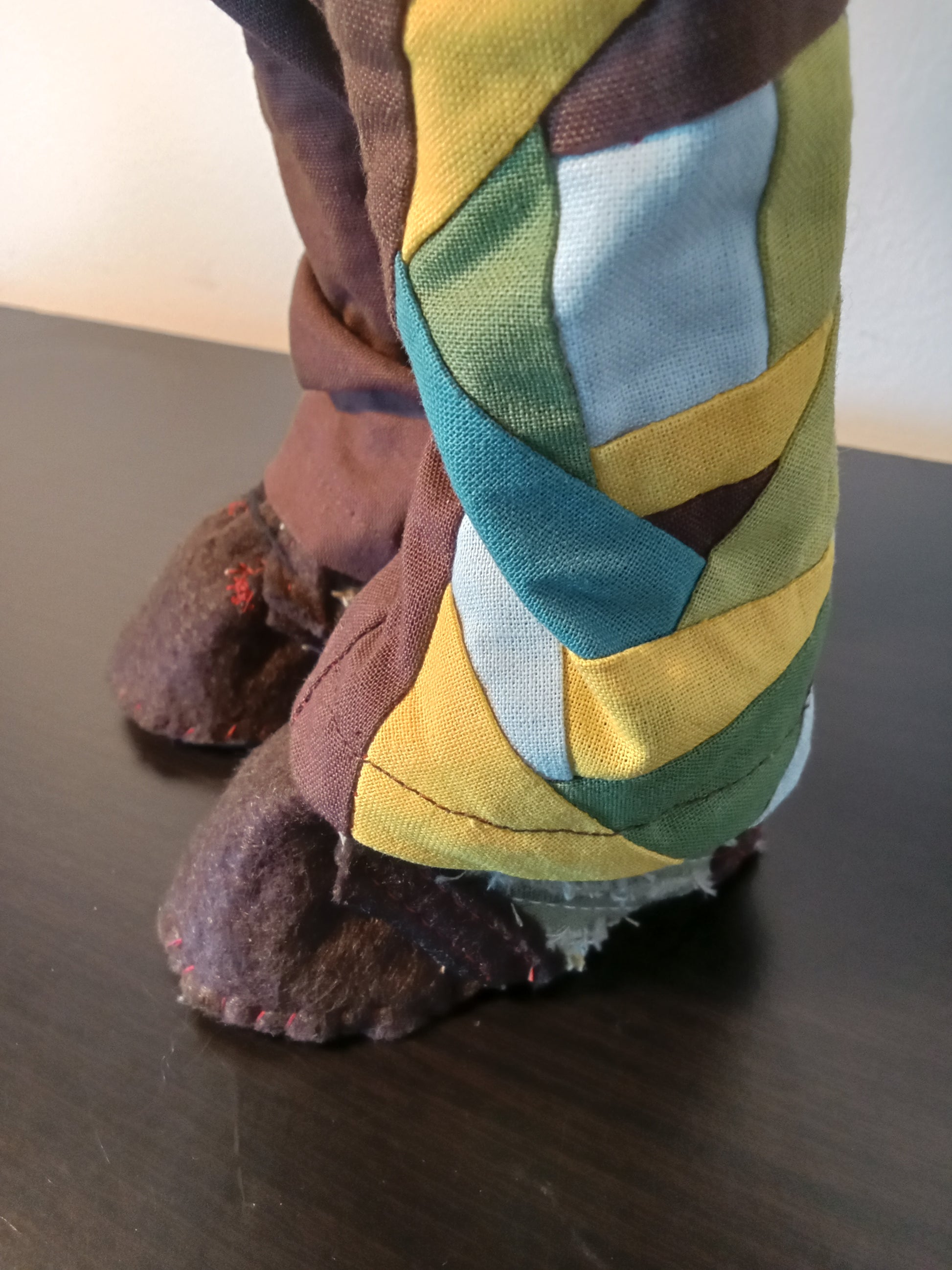 “Close up side view of Handmade collectible doll with red curly hair wearing a colorful boho outfit.”